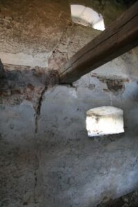 ZIEMIĘCICE, widoczna wielofazowość budynku pocz. XVI – XVIII w. – łęk łuku dawnego wejścia i belka stropu wtórnie wmurowana pod łękiem – widok z wnętrza budynku (fot. M. CHOROWSKA)