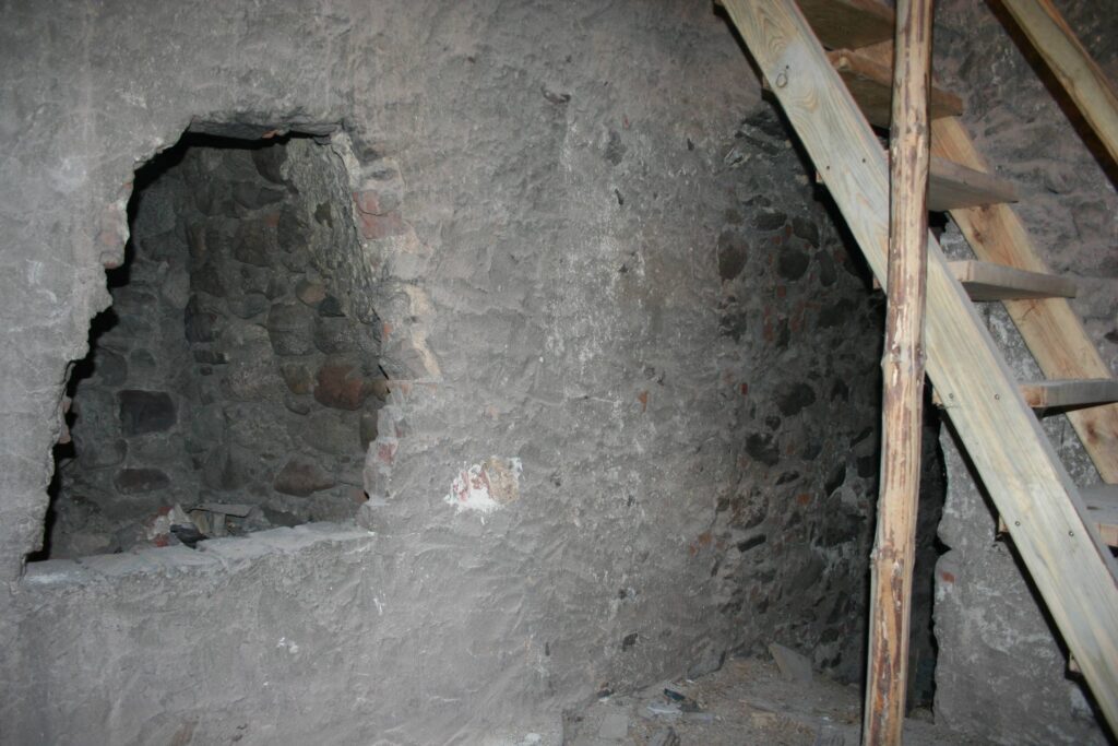 CHOCIANÓW, relikty kominka w pomieszczeniu wieży – widoczna wylotowa część przewodu z wykuciem i późniejszym zamurowaniem, detal z kamiennymi klińcami łuku, ok. 2005 (fot. A. Boguszewicz, Katalog Zamków i Dworów Obronnych Śląska [https://zamki.pwr.edu.pl/]. Licencja: CC BY-NC 4.0 [https://creativecommons.org/licenses/by-nc/4.0/] [https://creativecommons.org/licenses/by-nc/4.0/])