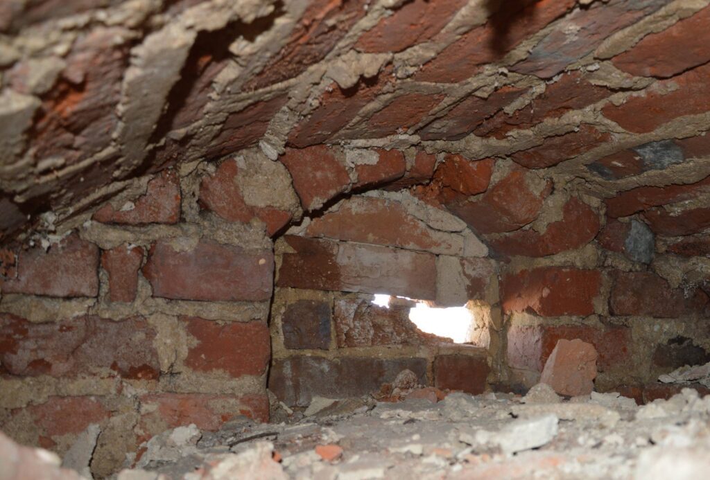 JĘDRZYCHÓW, Zamurowane okienko strzelnicze z fazy 1 na poziomie 5 kondygnacji wieży. Okienko znajduje się w rozległej wnęce zasklepionej łękiem odcinkowym (fot. P. Błoniewski)