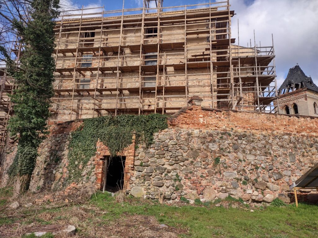 JĘDRZYCHÓW, Mur obwodowy zachowany po stronie wsch. stanowiący oskarpowanie plateau został nadbudowany murkiem ogrodzeniowym w XIX w. Na wprost wejście do sklepionej piwnicy pod plateau z XIX w. (fot. M. Chorowska)